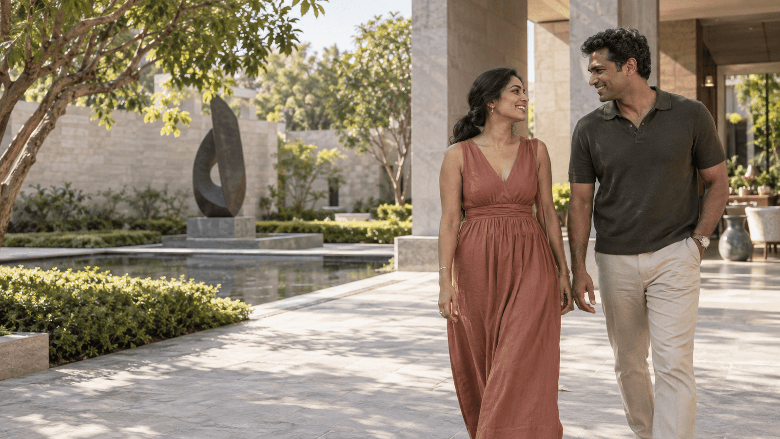 A couple walking together through a leafy courtyard.