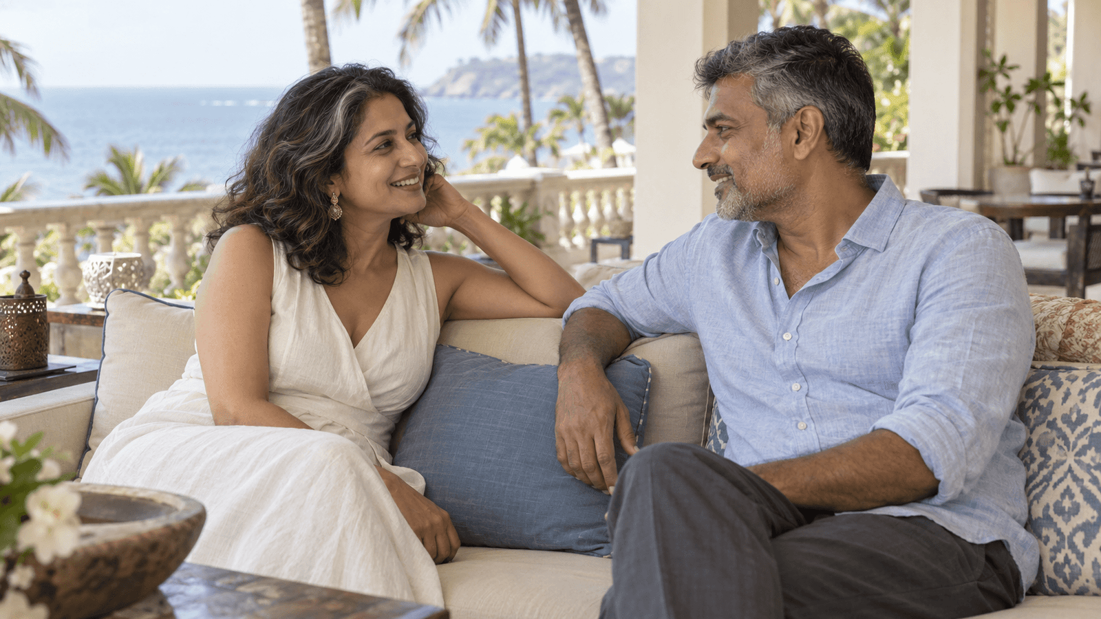Two adults talking together on a sunlit terrace.